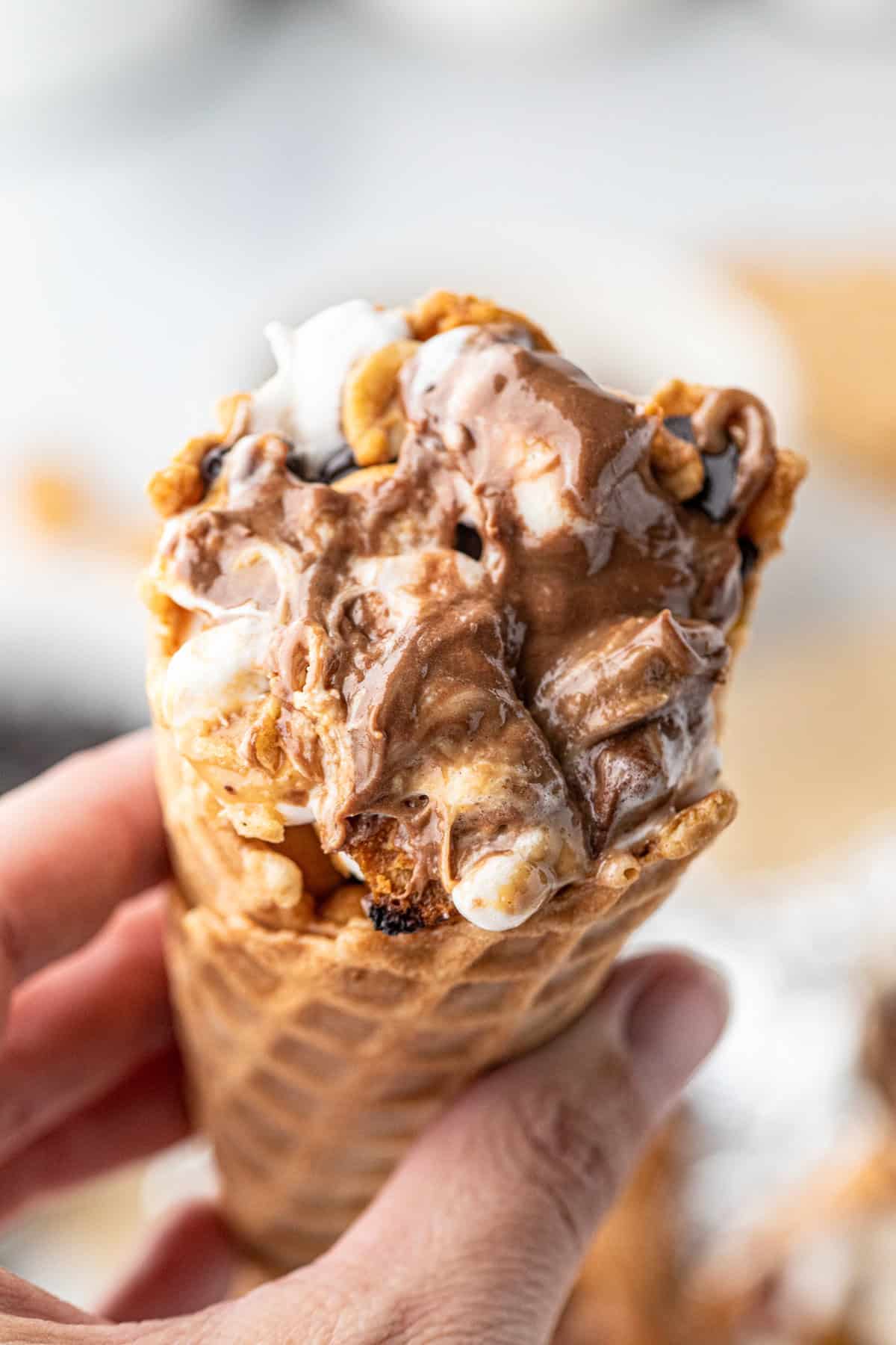 Campfire Cone being held in one hand oozing with melty goodness