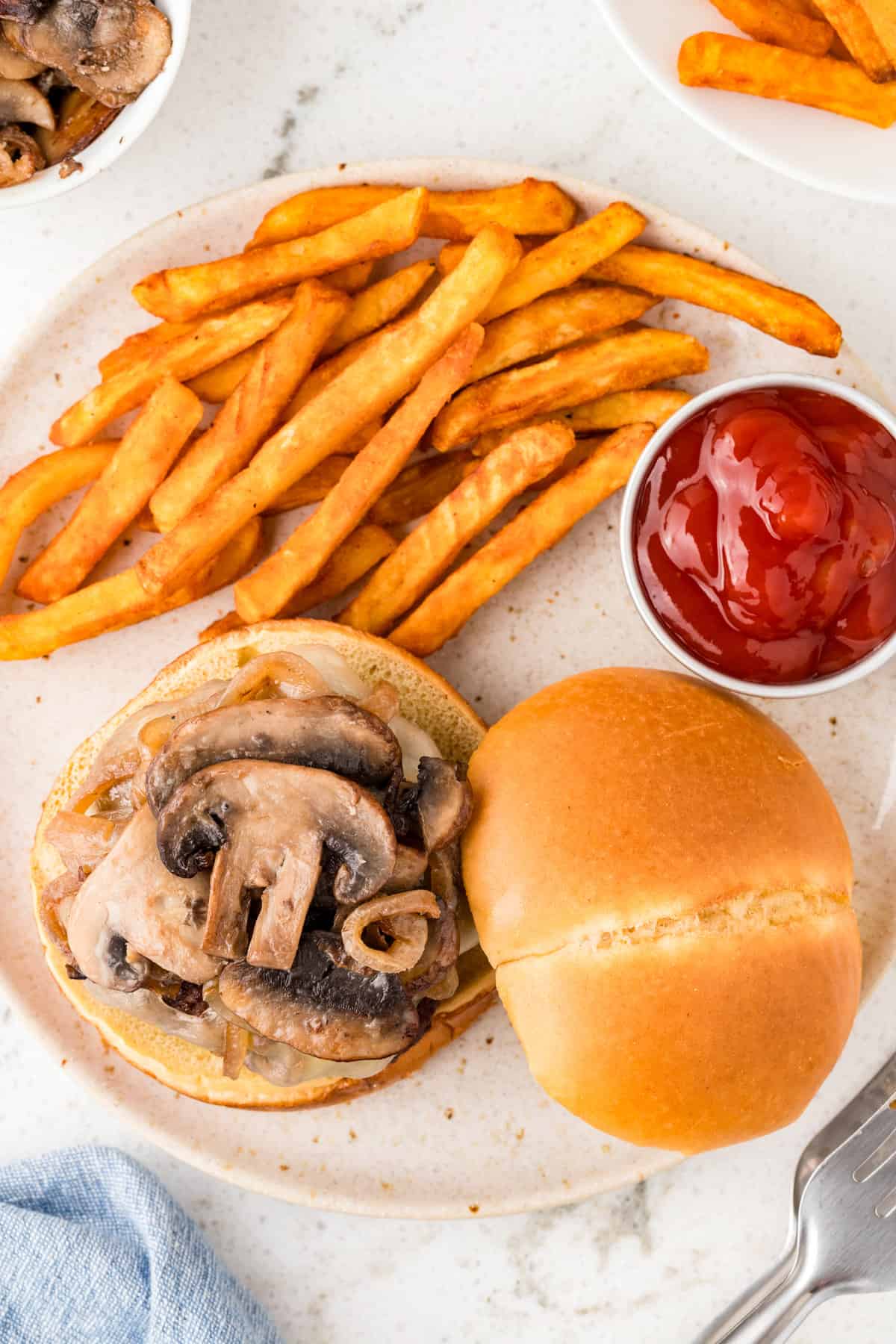Mushroom Swiss Burger on brioche bun with french fries and ketchup on plate