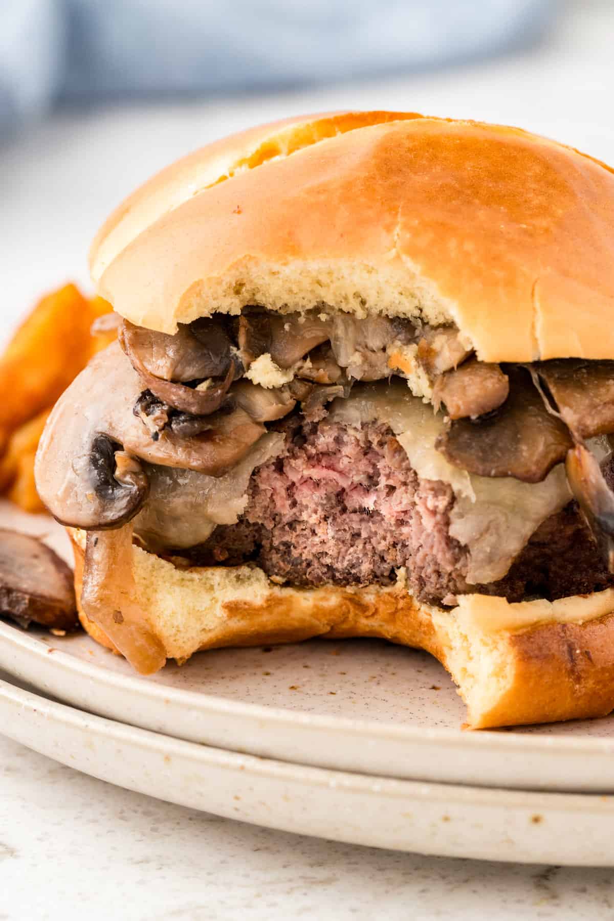 Mushroom Swiss Burger on plate with one bite taken