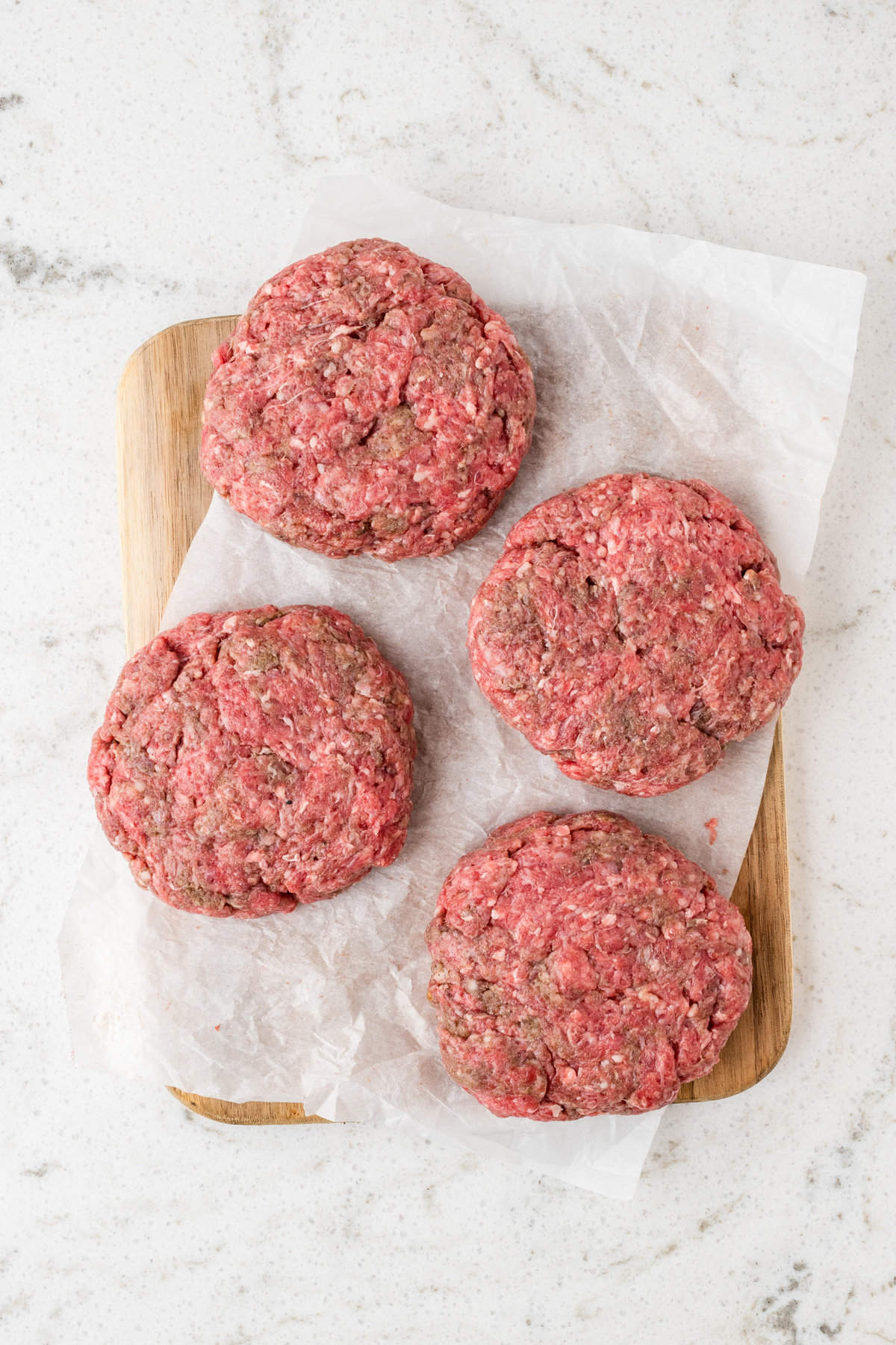 Seasoned beef formed and pressed into patties on parchment paper for Mushroom Swiss Burger recipe