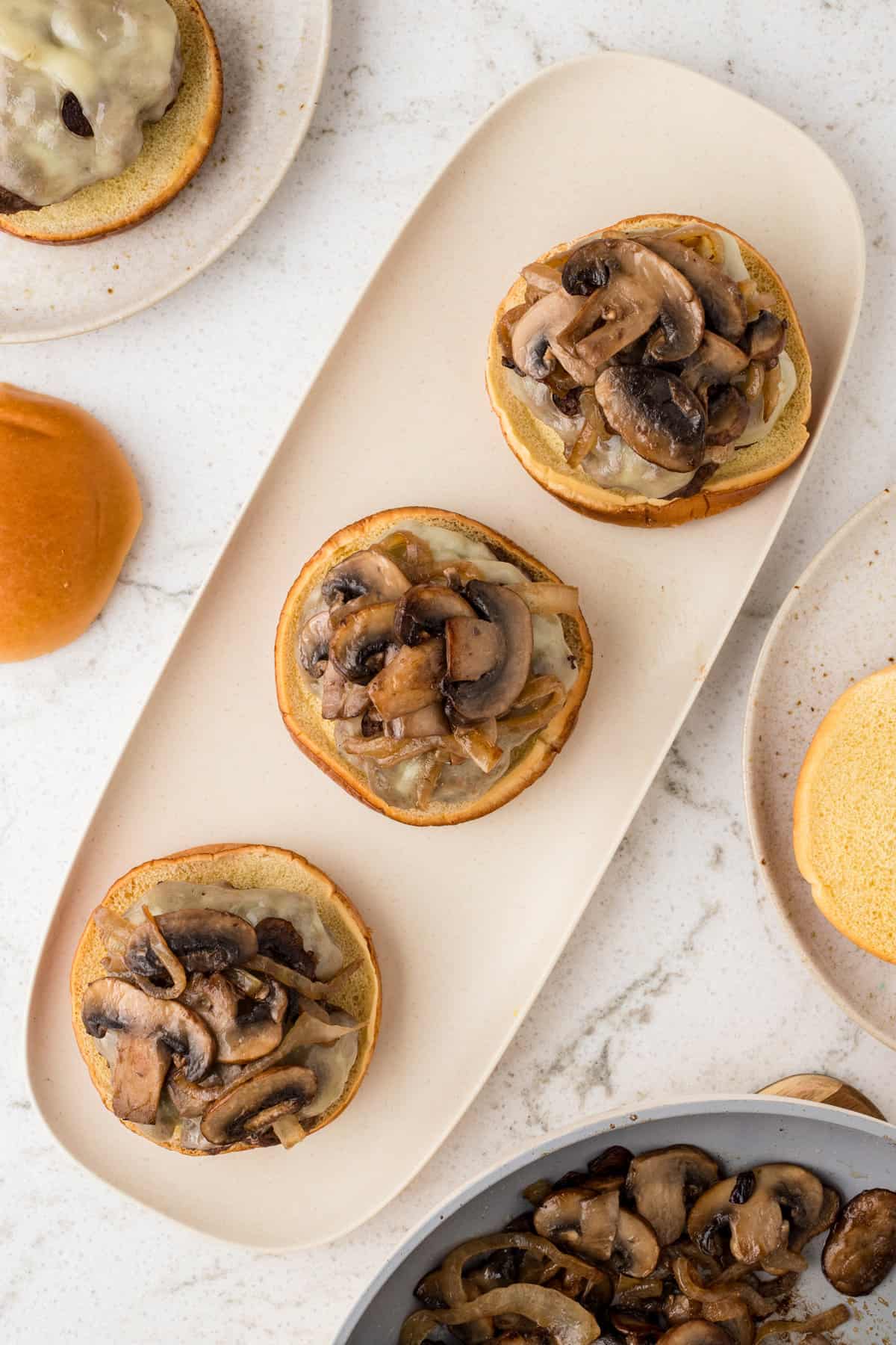 Adding cooked mushrooms over swiss cheese on burger for Mushroom Swiss Burger recipe