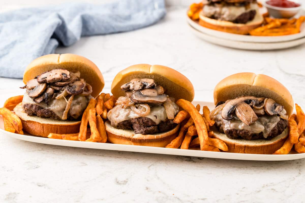 Mushroom & Swiss Burgers lined on serving tray with french fries