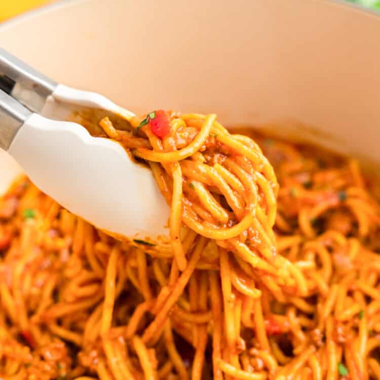 A Tonges holding taco spaghetti outside of the dutch oven.