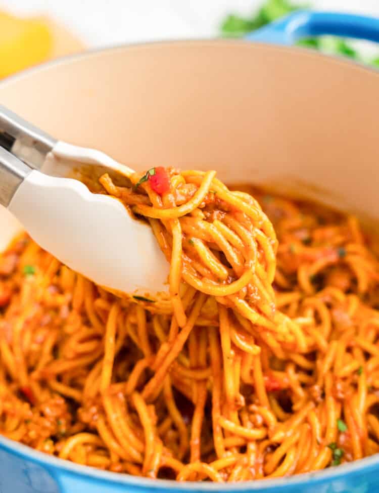 A Tonges holding taco spaghetti outside of the dutch oven.