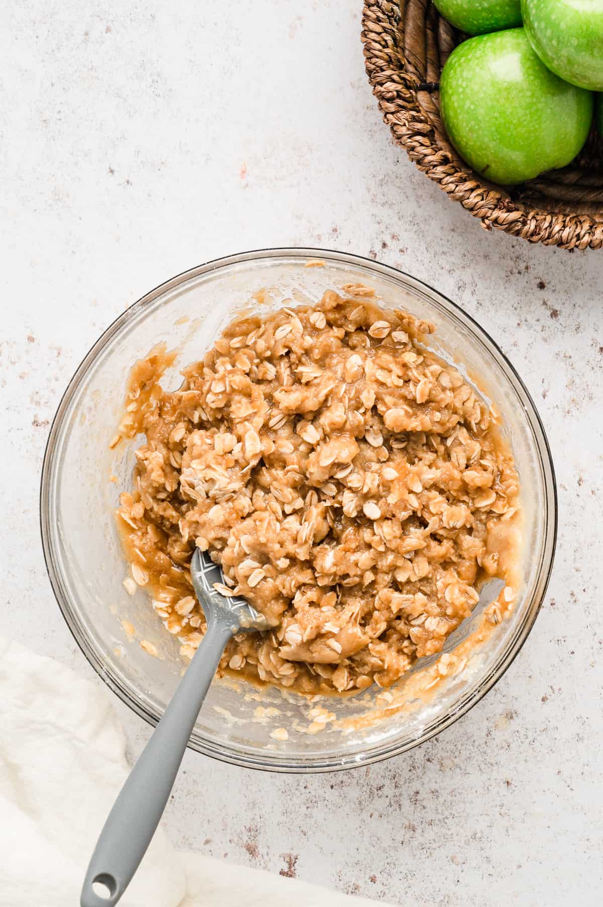 Combined topping ingredients for Easy Apple Crisp recipe in mixing bowl with spoon