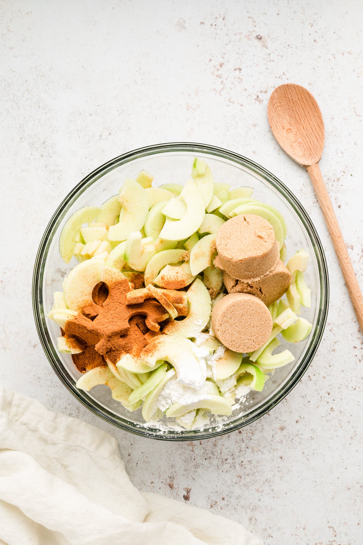 Prepared Granny Smith apples and seasoning ingredients in glass mixing bowl for Easy Apple Crisp