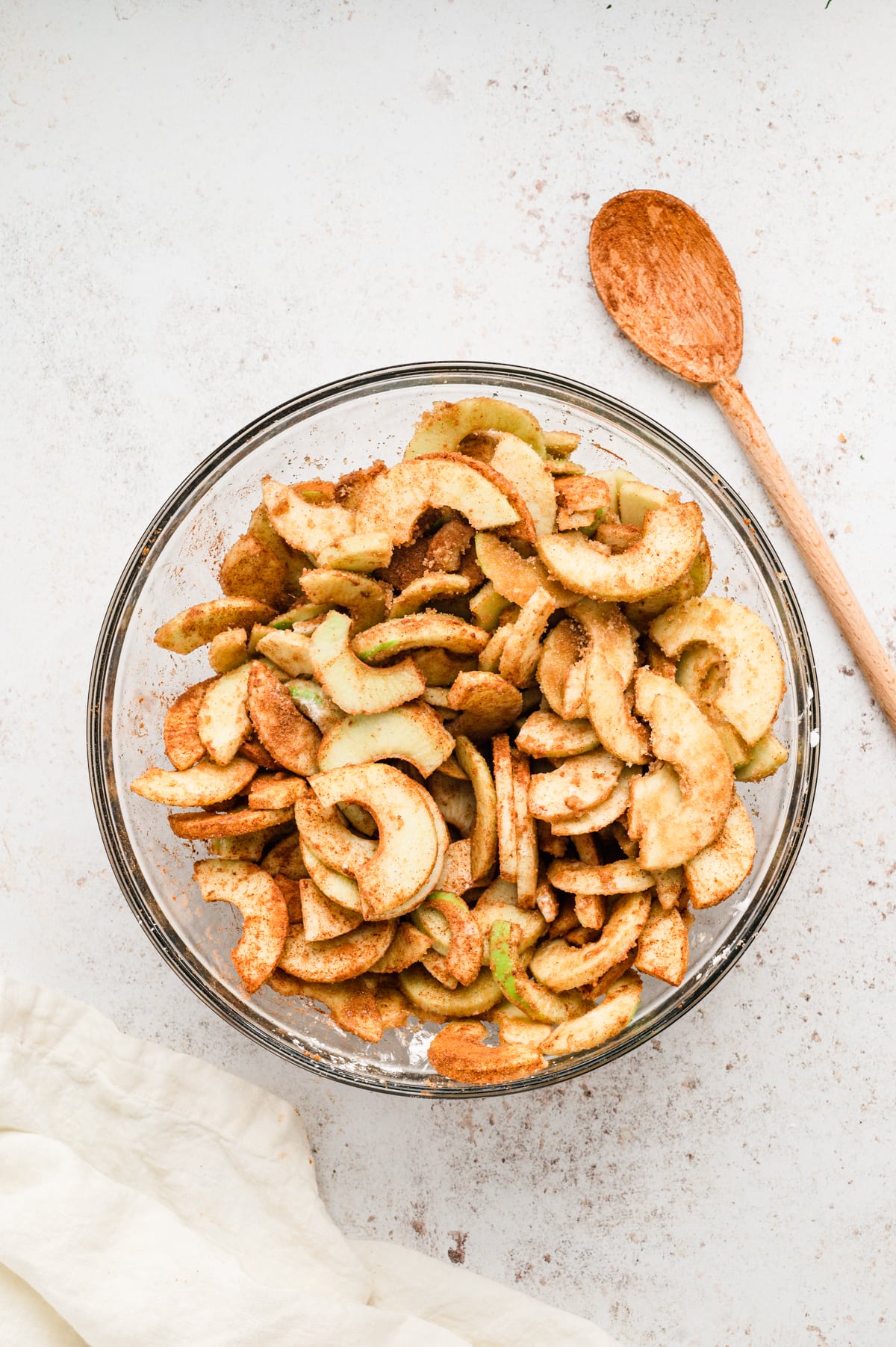 Prepared Granny Smith apples and seasoning ingredients in glass mixing bowl for Easy Apple Crisp