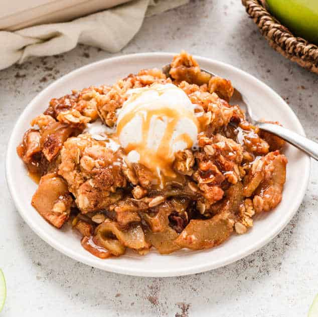 Easy Apple Crisp Recipe in serving bowl topped with vanilla ice cream and caramel