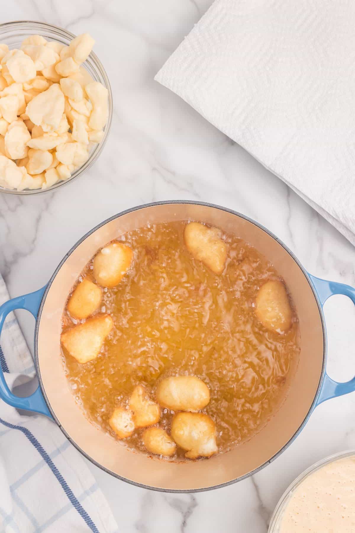 Batter-dipped Cheese Curds in boiling oil in large stovetop pot