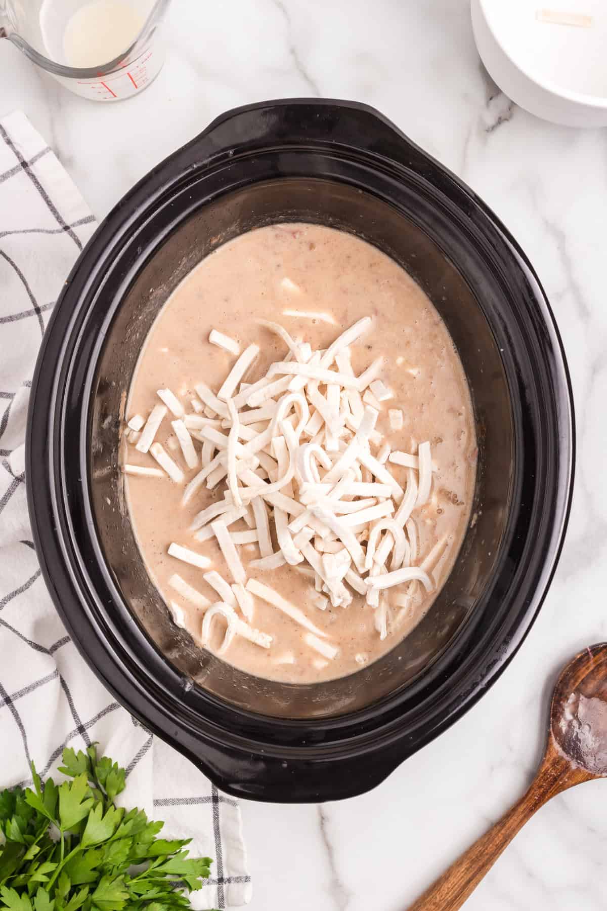 Adding noodles to crock pot ingredients for Crock Pot Beef and Noodles recipe