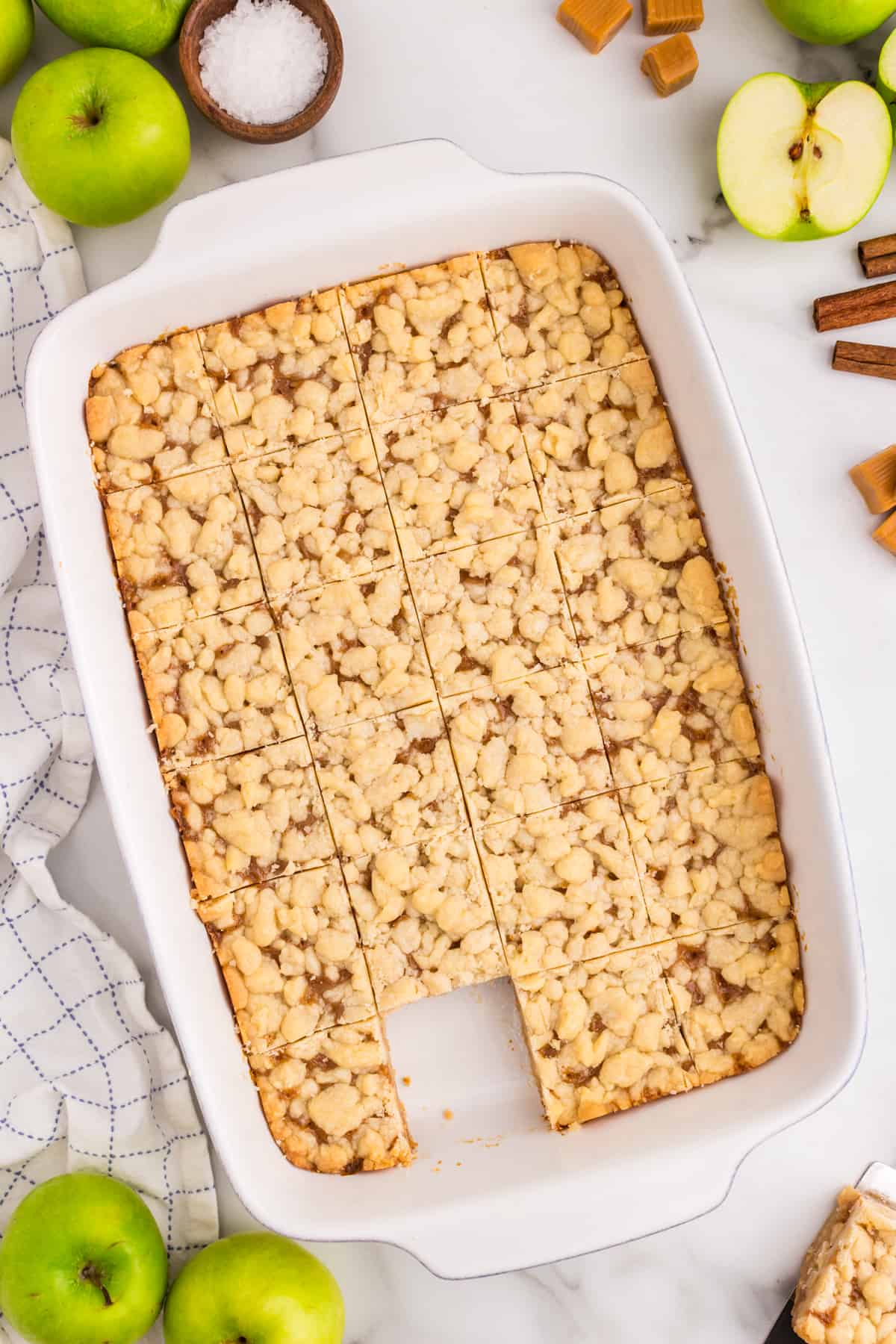 Salted Caramel Apple Butter Bars cut into squares in baking dish with one piece already eaten