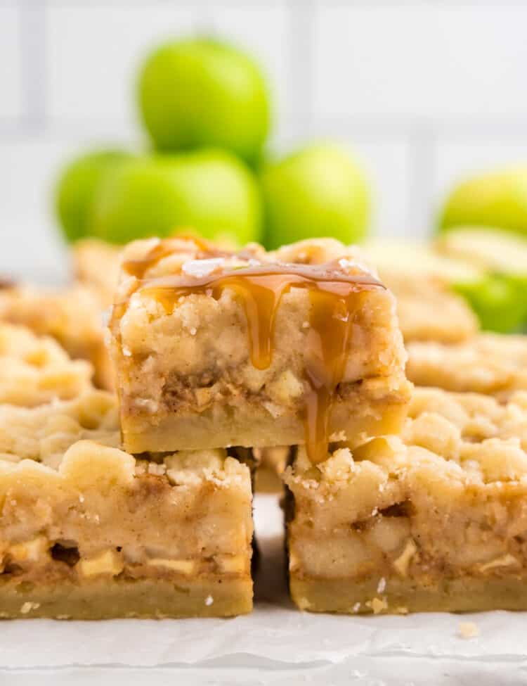 Salted Caramel Apple Butter Bars cut into squares and stacked on serving plate with Granny Smith apples in background