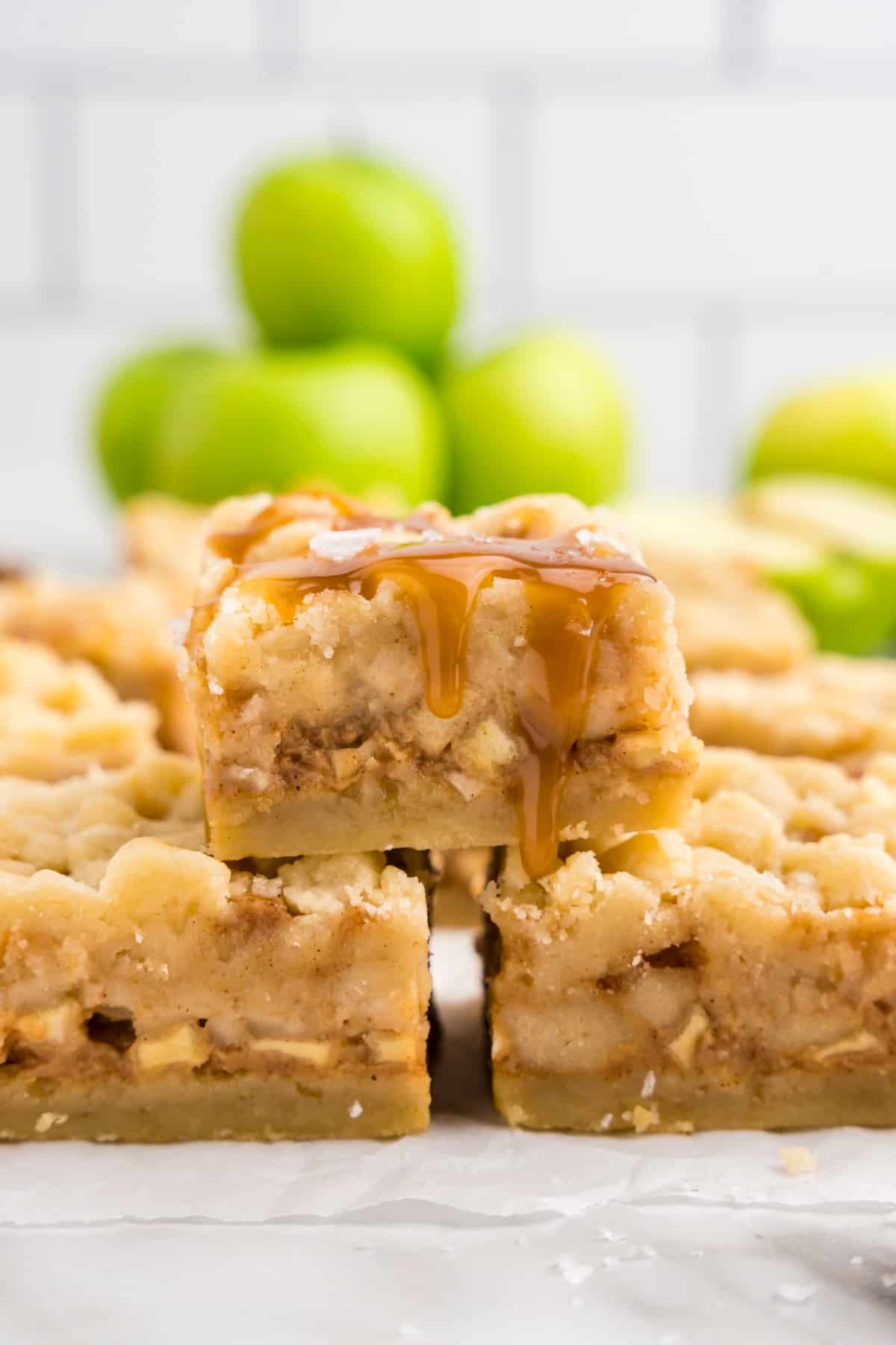 Salted Caramel Apple Butter Bars cut into squares and stacked on serving plate with Granny Smith apples in background