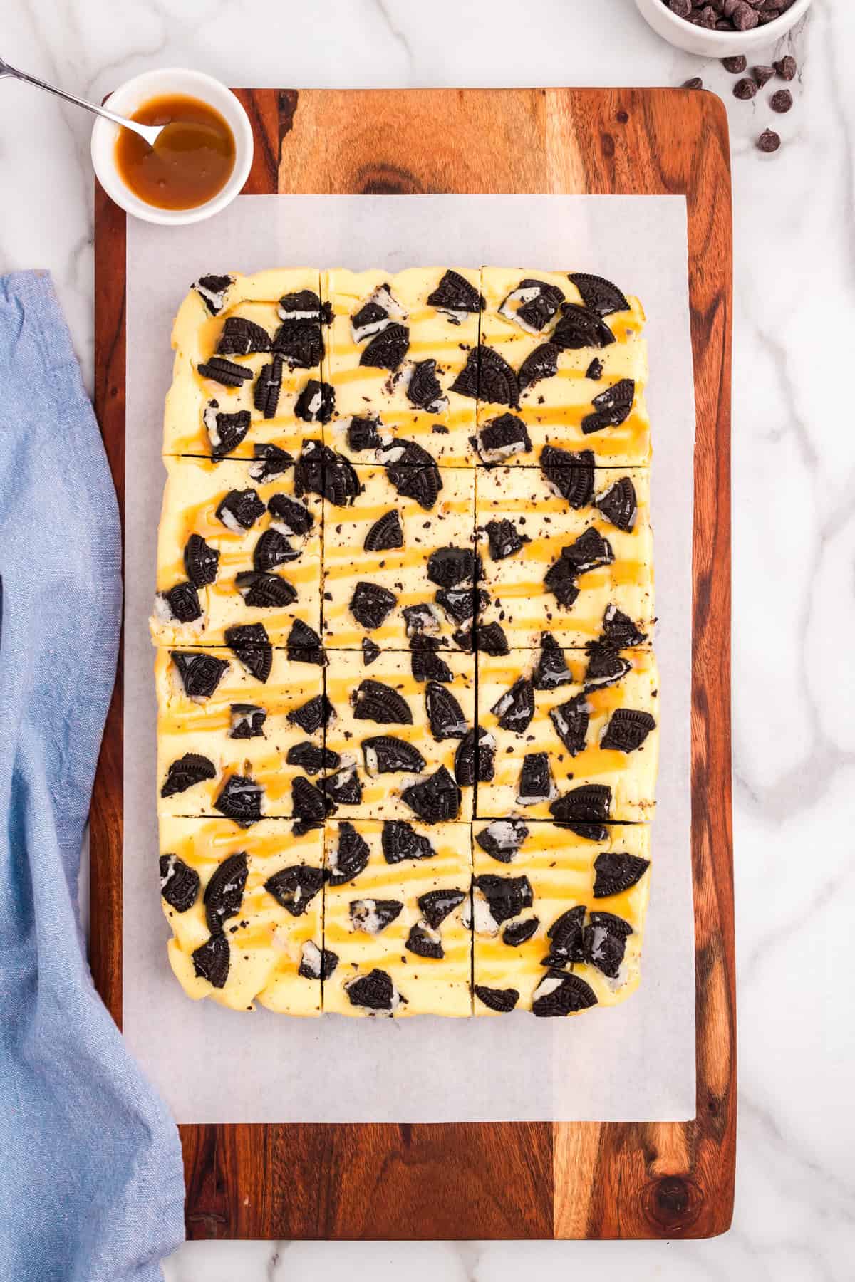 Cutting Slutty Cheesecake Bars into squares over parchment lined cutting board