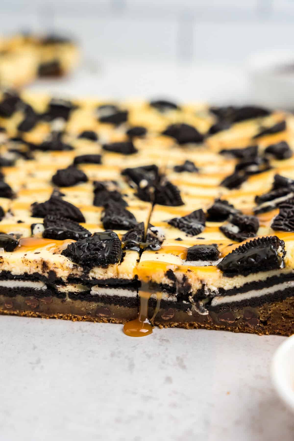 Slutty Cheesecake Bars cut into squares dripping with caramel drizzle