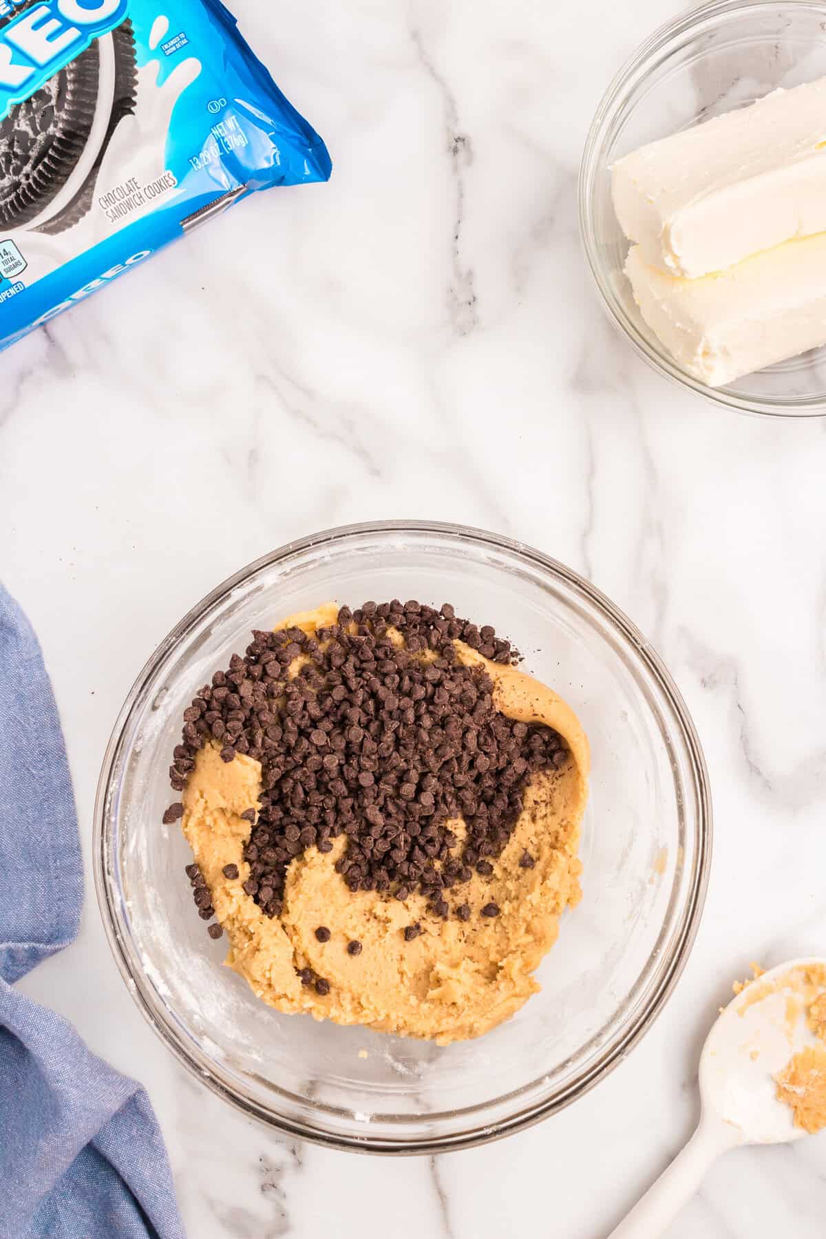 Adding chocolate chips to Slutty Cheesecake Bars cookie base in small mixing bowl