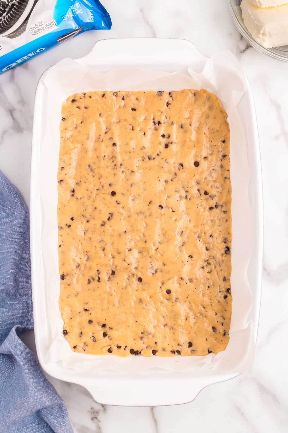 Pressing cookie dough base into 9x13 baking dish for Slutty Cheesecake Bars recipe