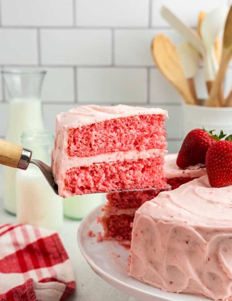 Using a spatula to lift a piece of Strawberry Cake from cake plate
