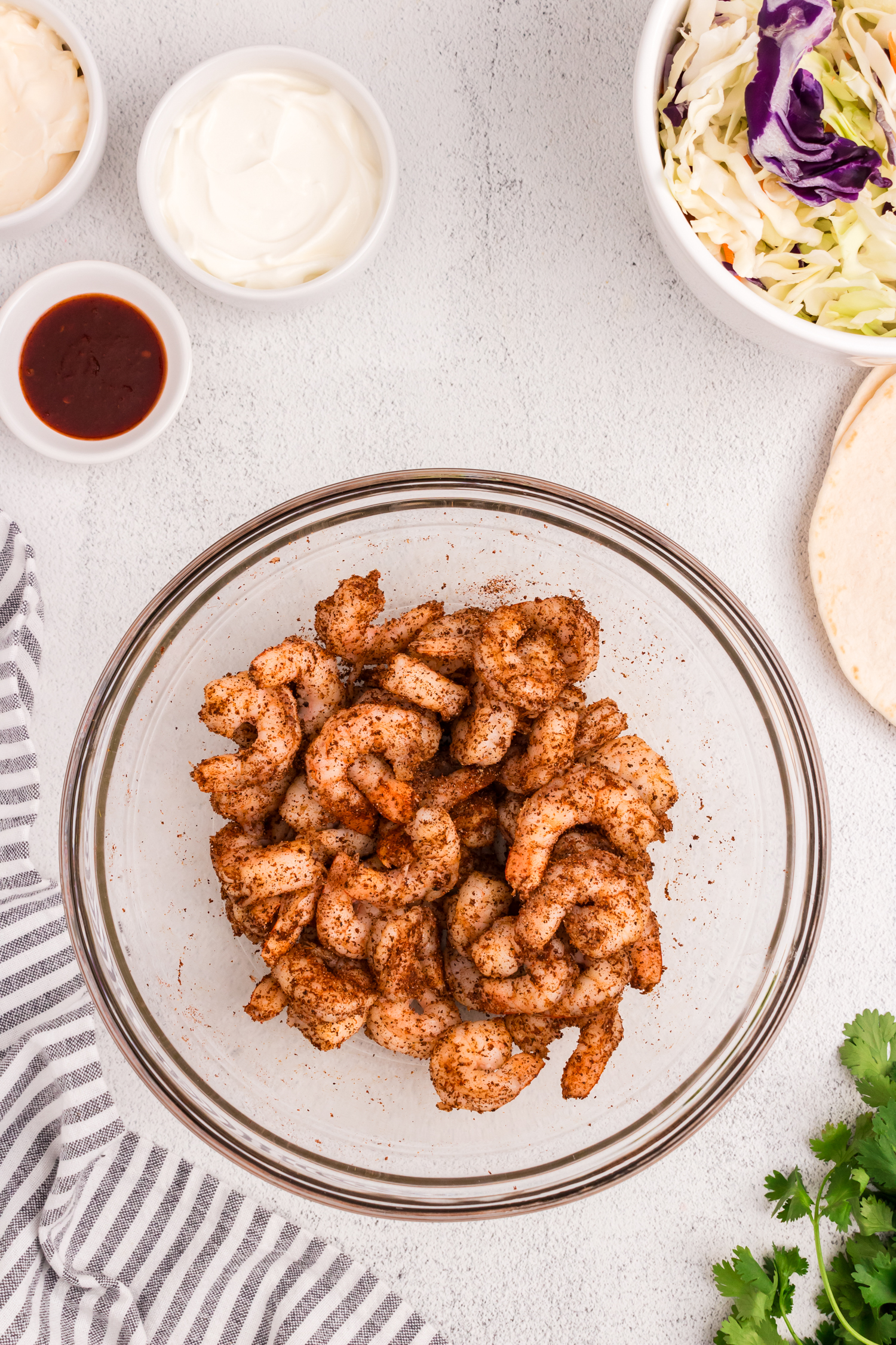 Shrimp coated in seasoning mixture for Baja Shrimp Tacos recipe in glass mixing bowl