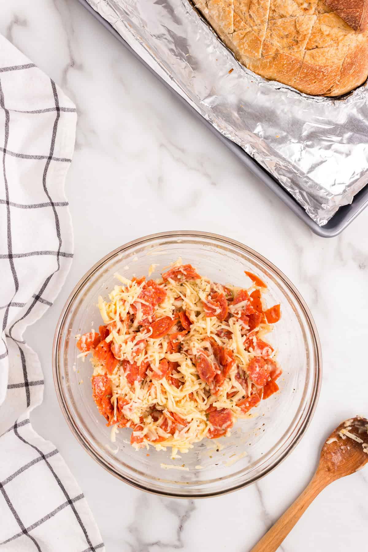 Pizza stuffing combined in glass mixing bowl for Pull Apart Pizza Bread recipe