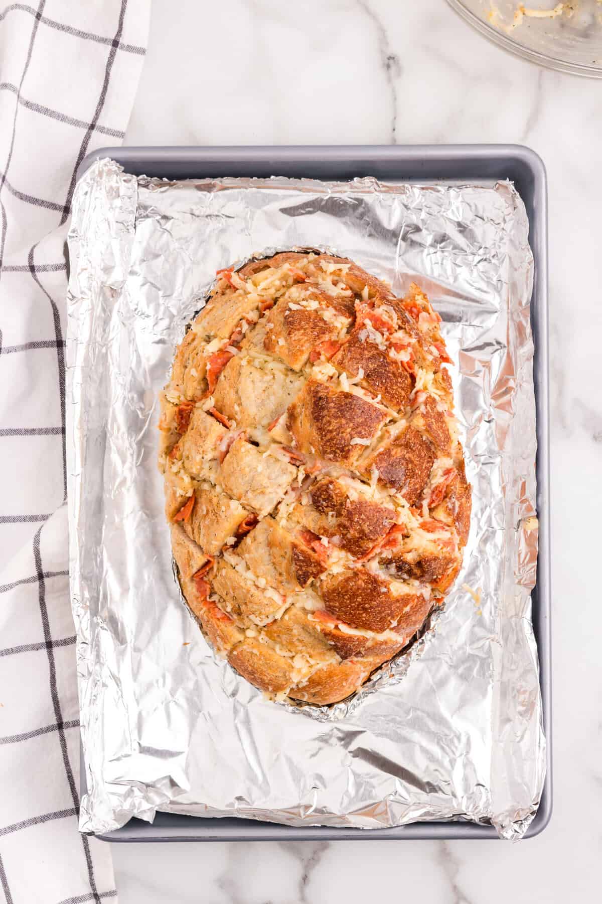 Pull Apart Pizza Bread stuffed with pizza ingredients on tinfoil lined baking sheet