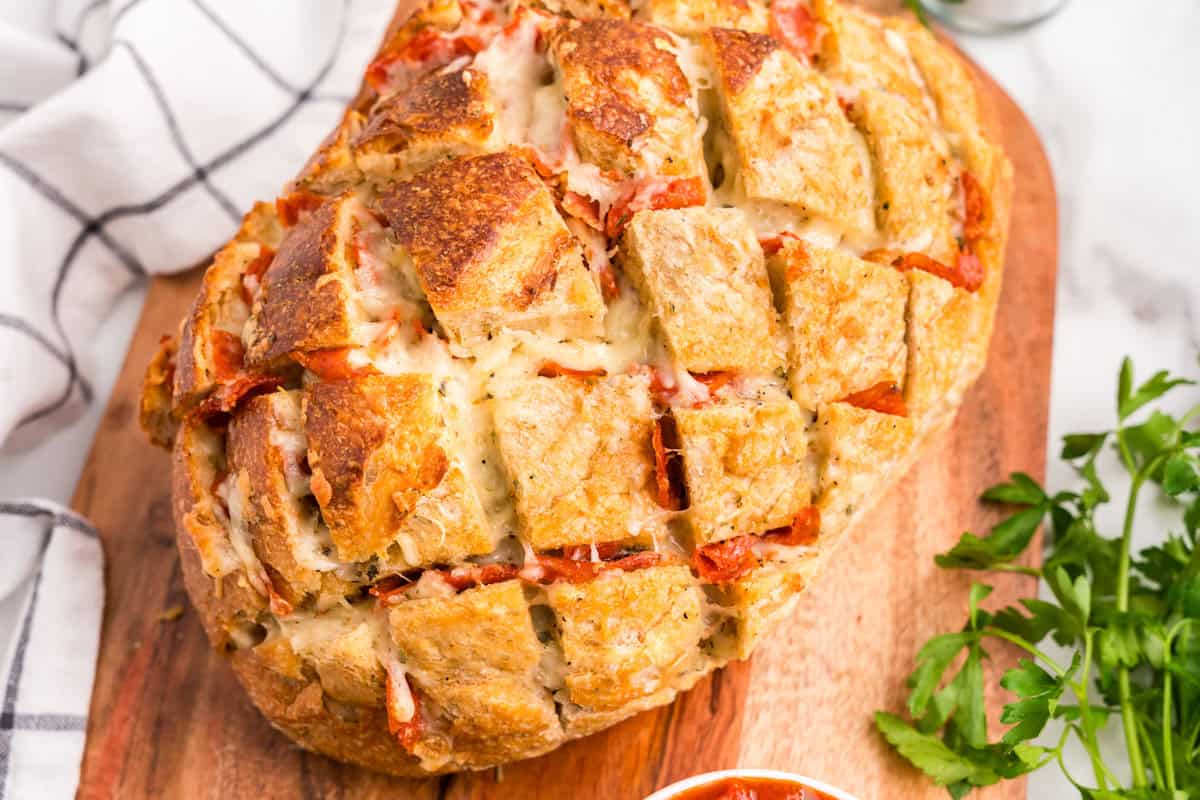Pull Apart Pizza Bread on wooden platter with marinara dipping sauce in small bowl