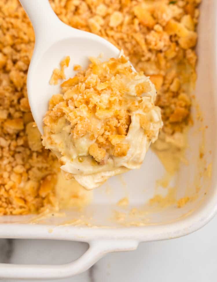 Using large spoon to sccop Ritz Cracker Chicken Casserole from baking dish
