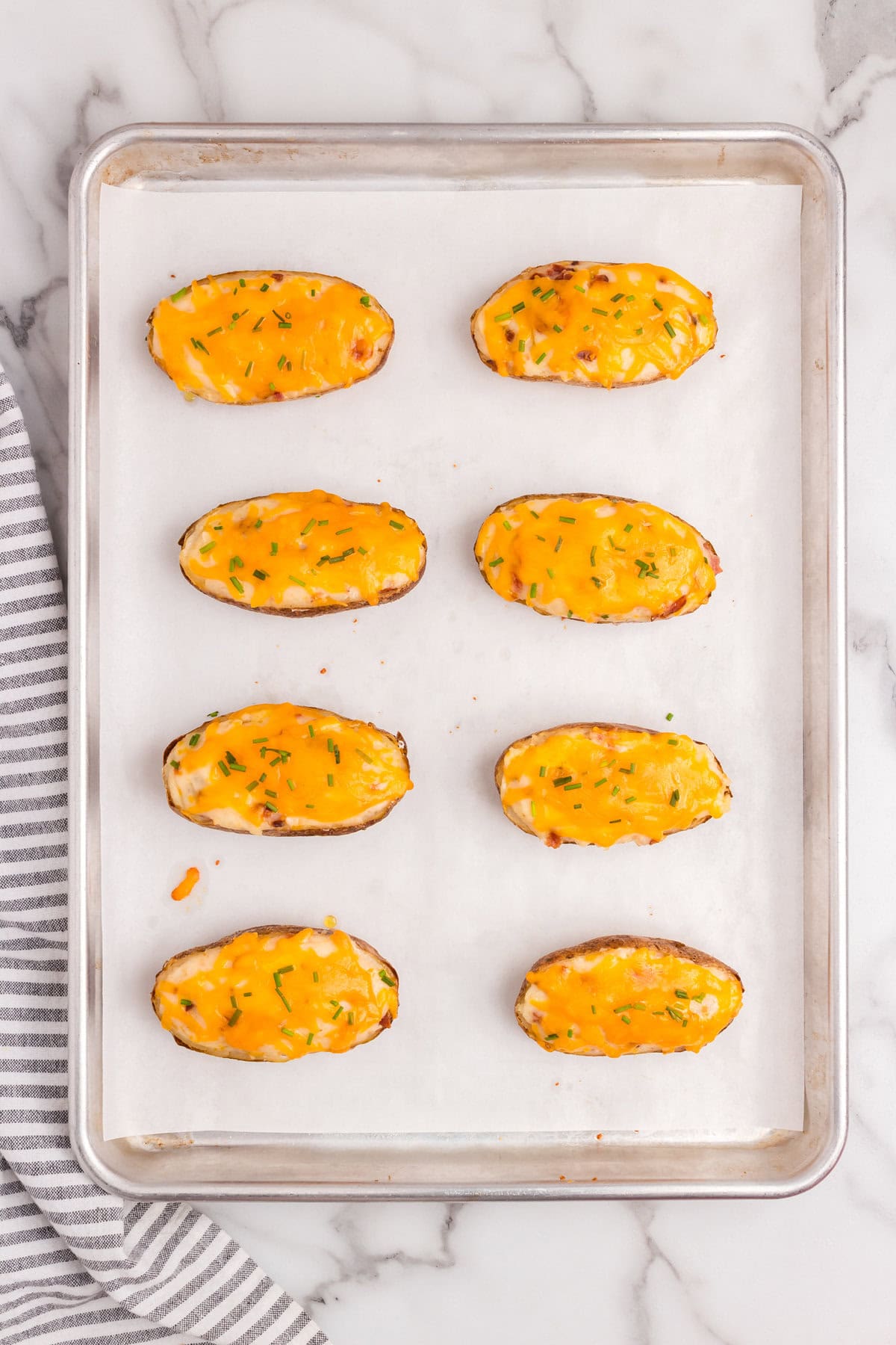 Twice Baked Potatoes out of the oven for the second time on parchment-lined baking sheet