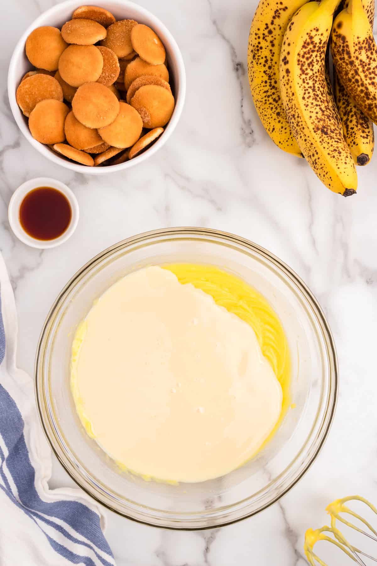 Adding in additional ingredients to Banana Pudding mixture in glass bowl