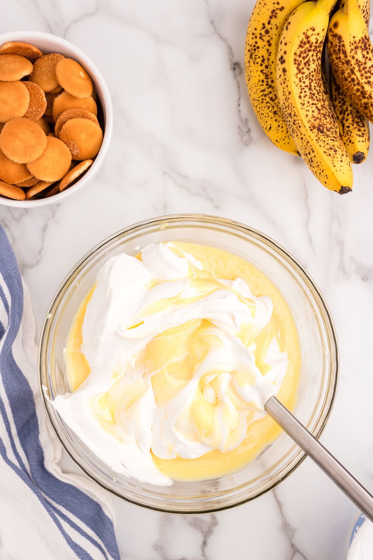 Folding whipped topping into Banana Pudding mixture in glass bowl