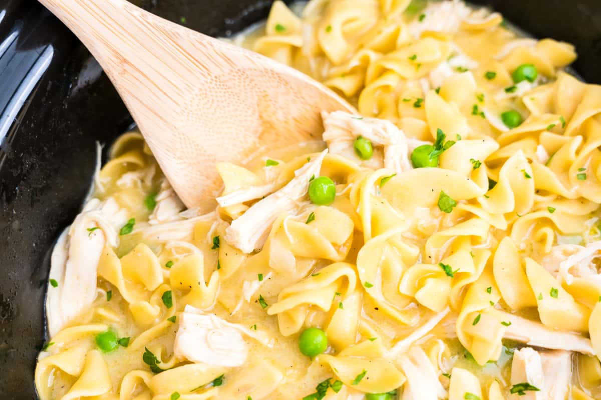 Using wooden spoon to stir Crock Pot Chicken and Noodles from crock pot