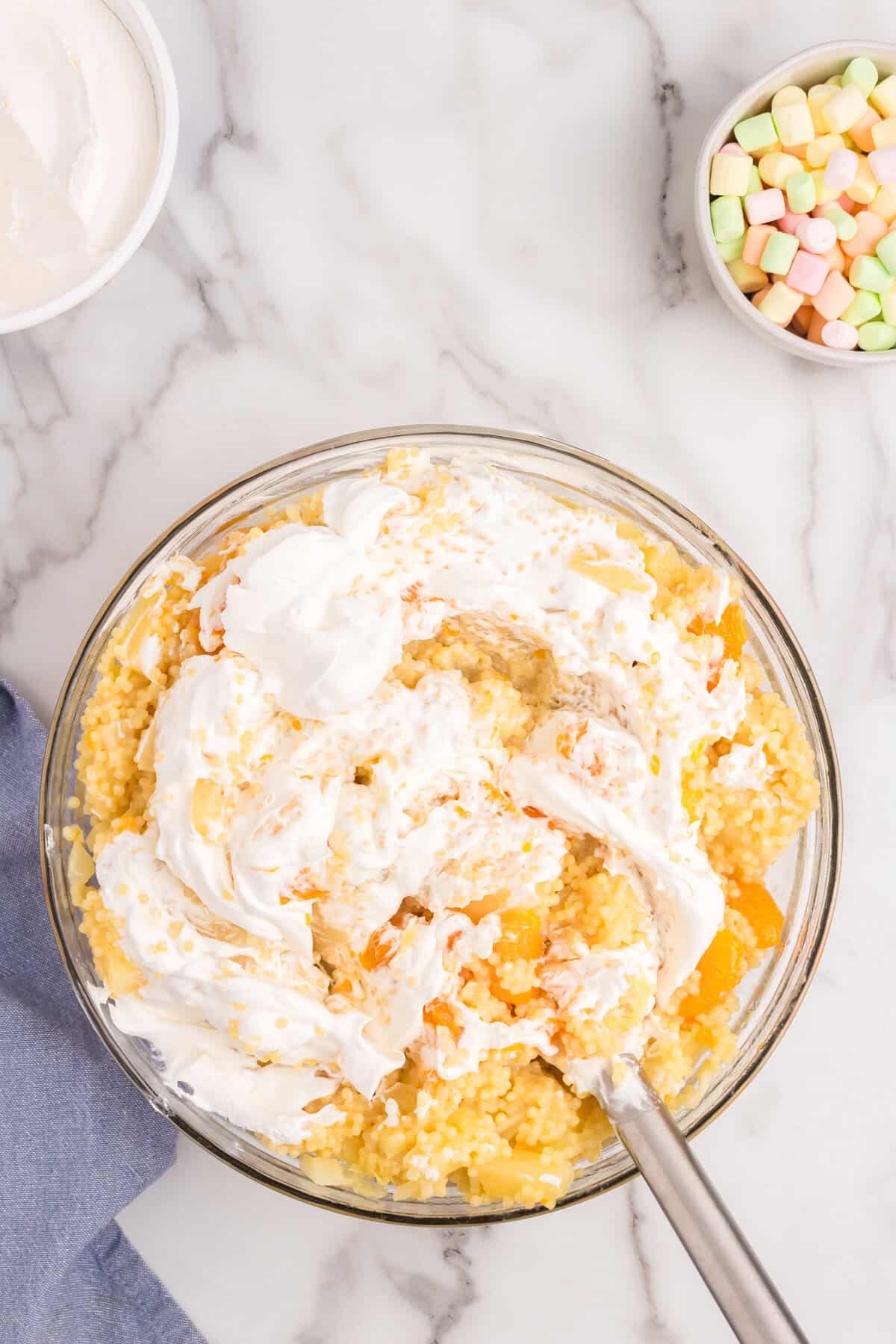 Carefully folding in whipped topping with Frog Eye Salad ingredients in large bowl