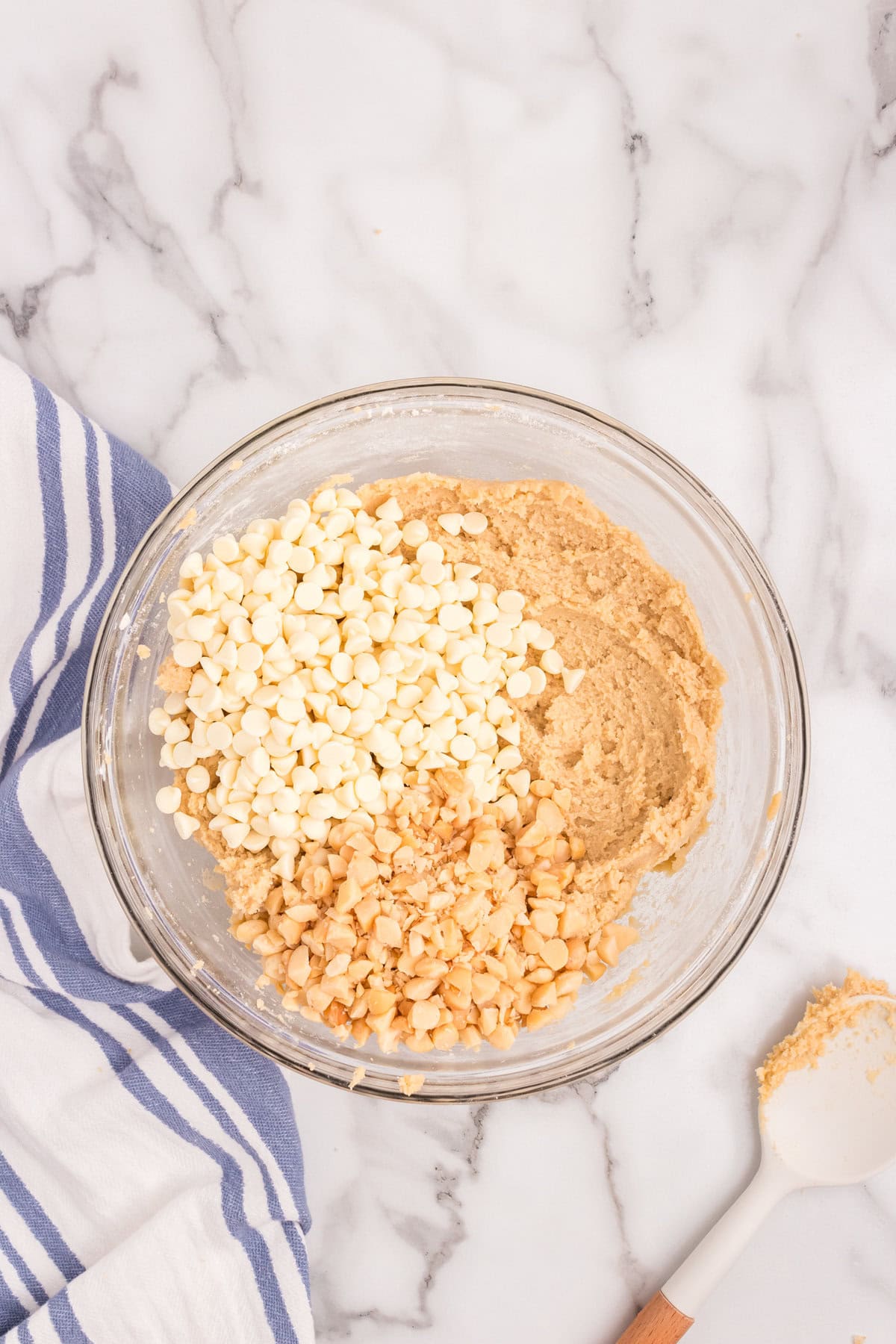 Adding white chocolate chips and macadamia nuts into Macadamia Nut and White Chocolate Cookies mixture