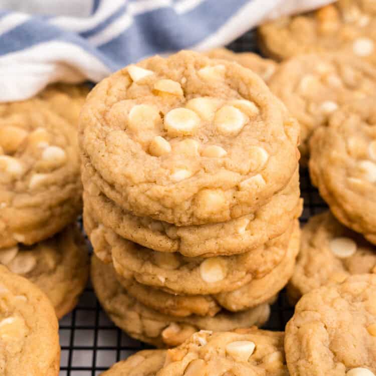 Closeup square image of White Chocolate Macadamia Nut Cookies stacked on cooling rack
