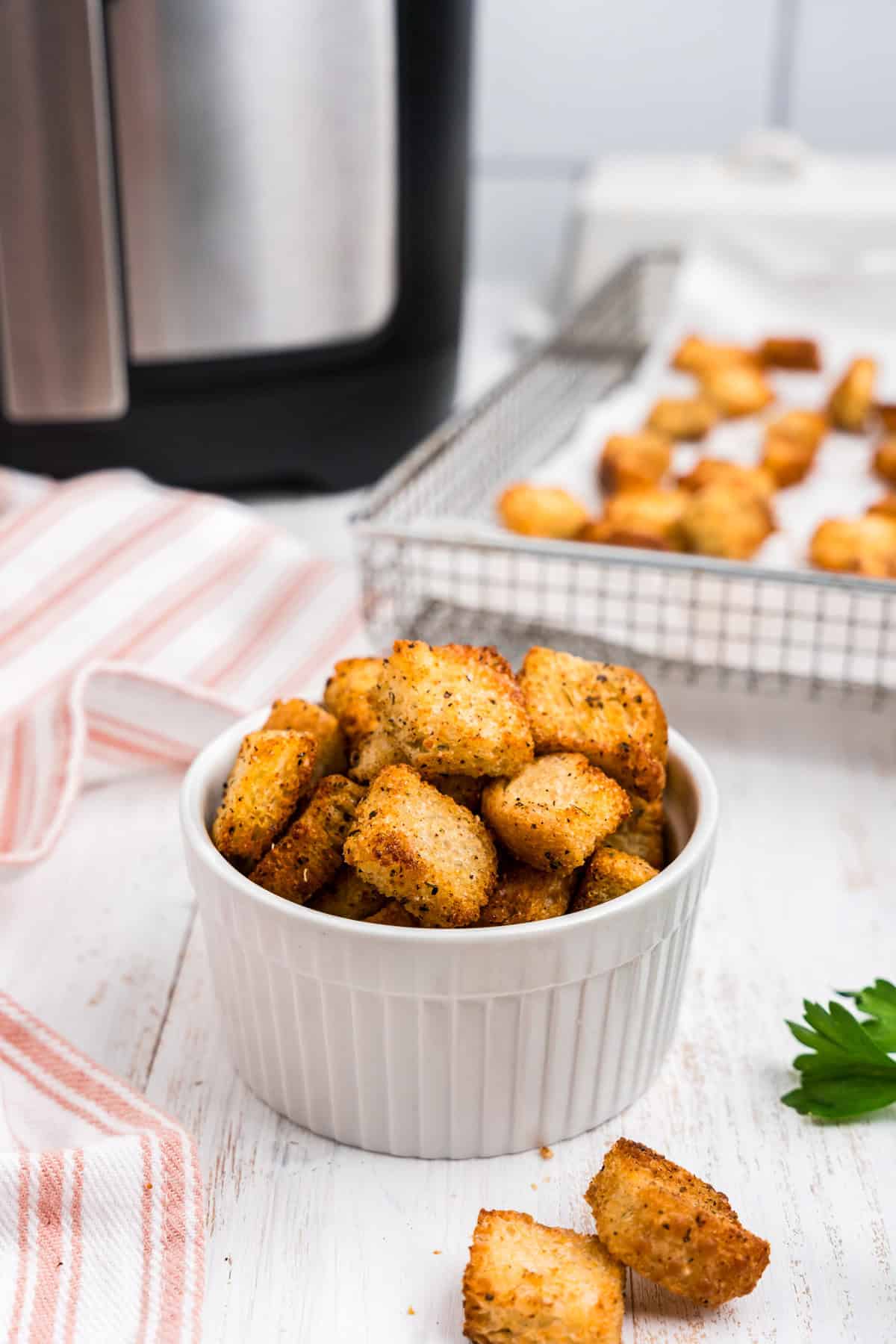 Air Fryer Croutons in small serving bowl and some in the air fryer basket