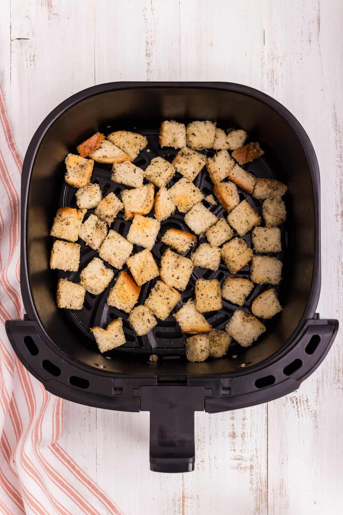 Seasoned bread cubes arranged in air fryer prior for Air Fryer Croutons