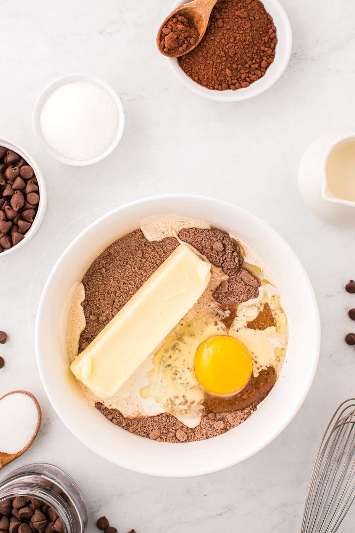 Adding butter and egg to Chocolate Thumbprint Cookies mixture in bowl