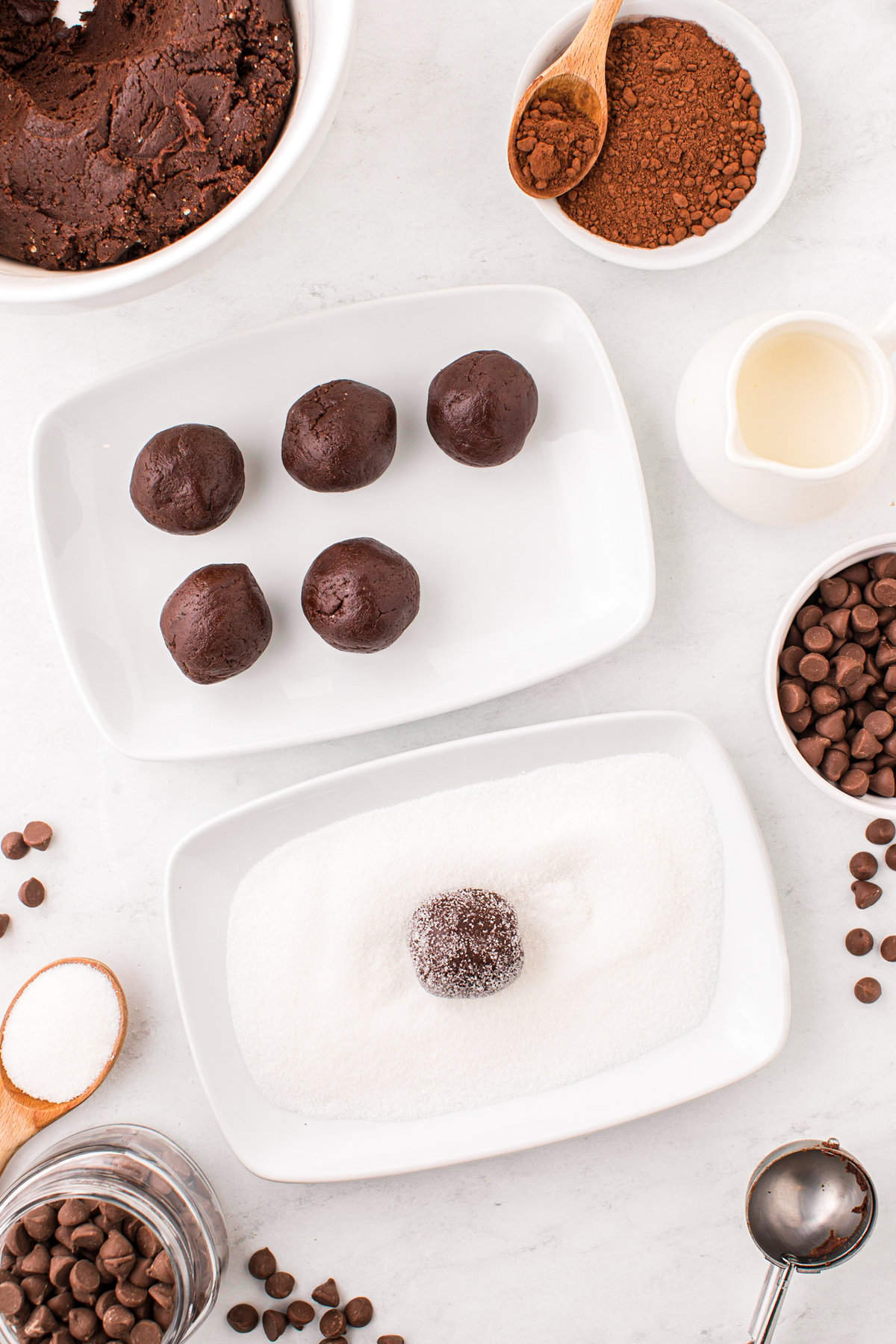 Rolling Chocolate Thumbprint Cookies dough balls in shallow bowl to coat with sugar