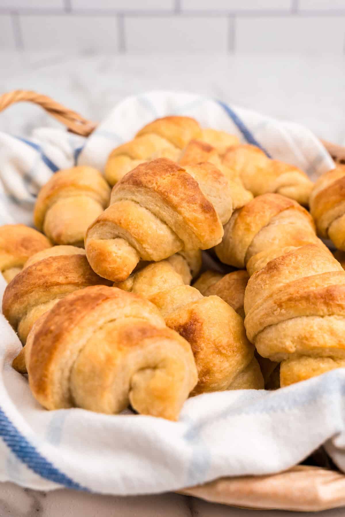 Homemade Crescent Rolls arranged in shallow serving bowl lined with a linen towel