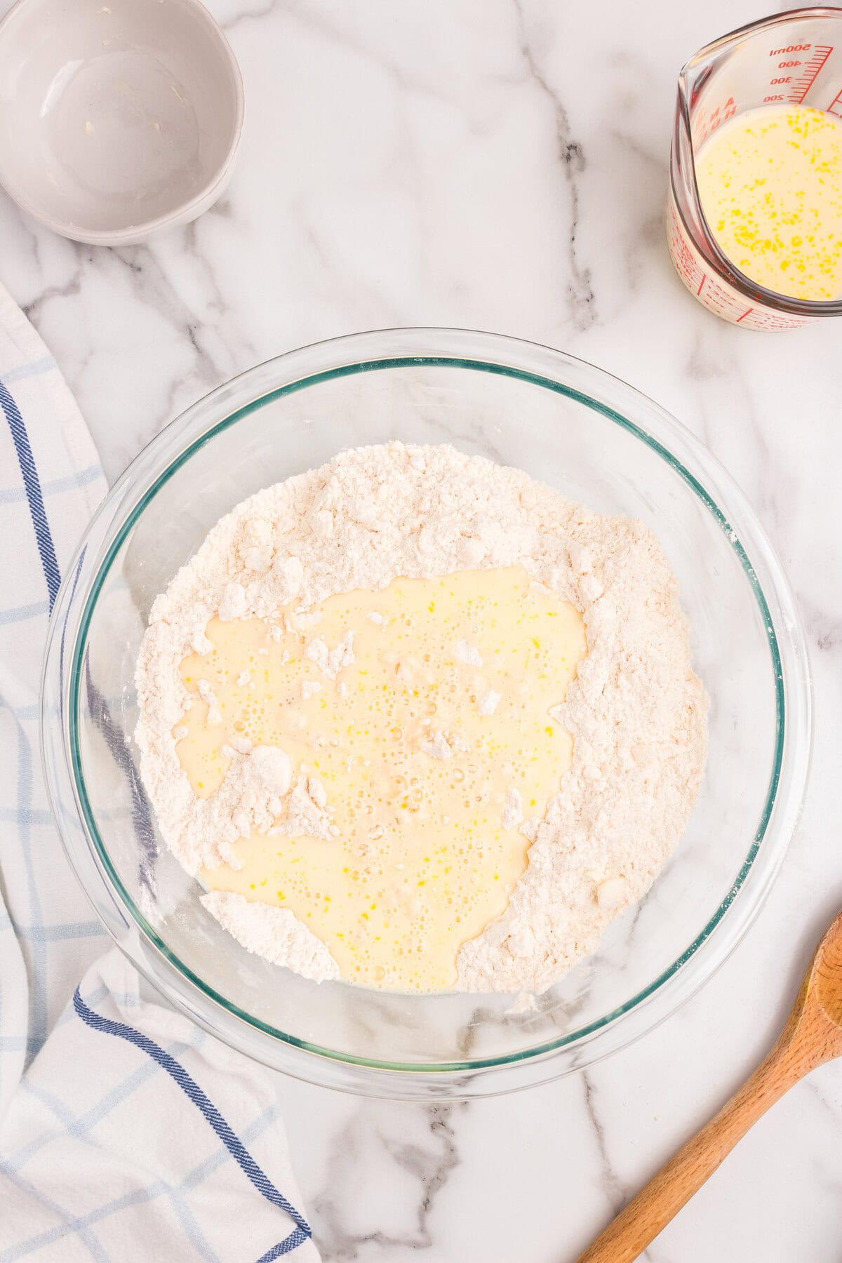 Combining dry and wet ingredients for Homemade Crescent Rolls in glass mixing bowl