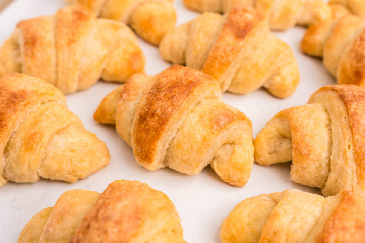 Homemade Crescent Rolls arranged on parchment-lined sheet pan hot out of the oven