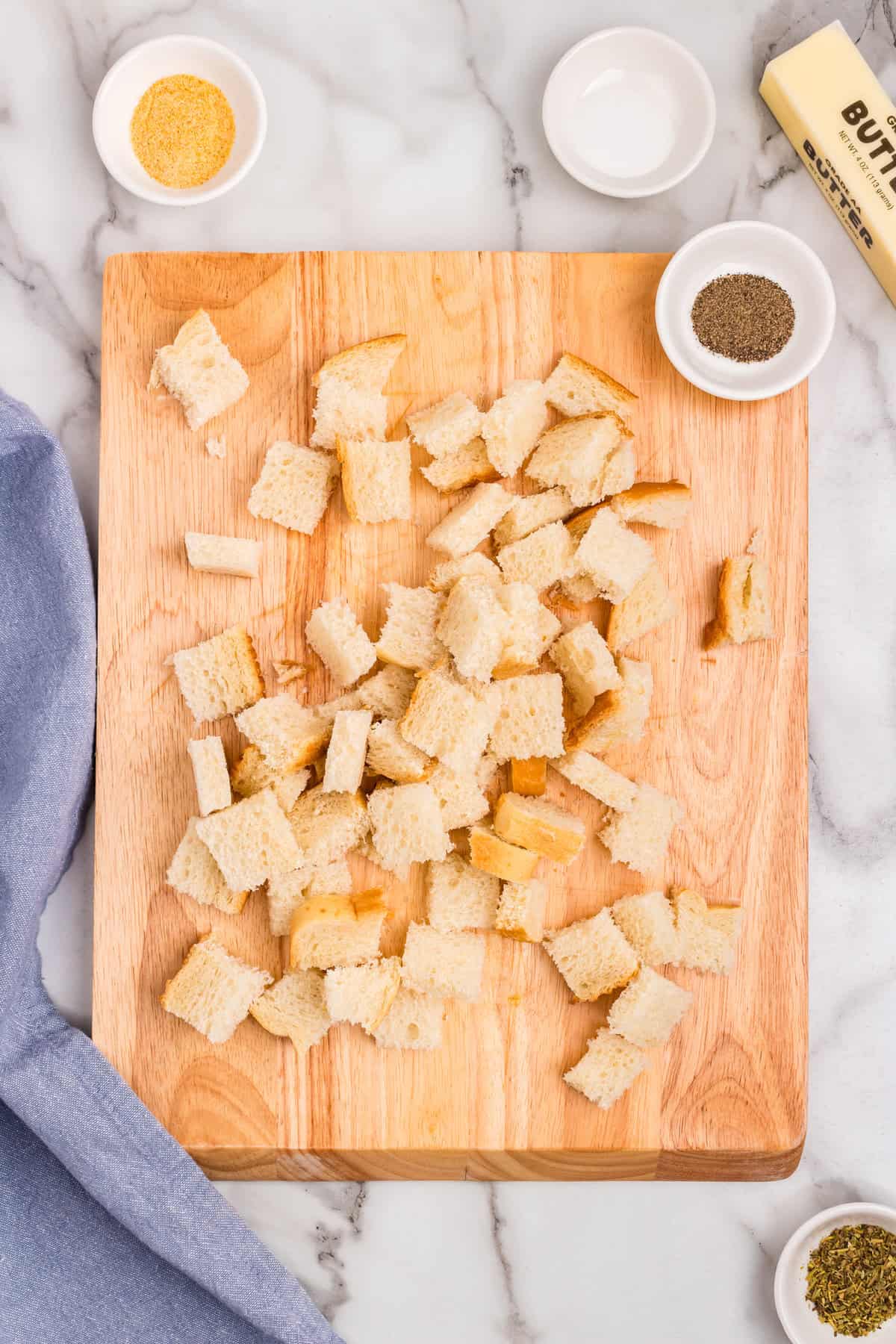 Cubing bread for Homemade Croutons recipe on wooden cutting board