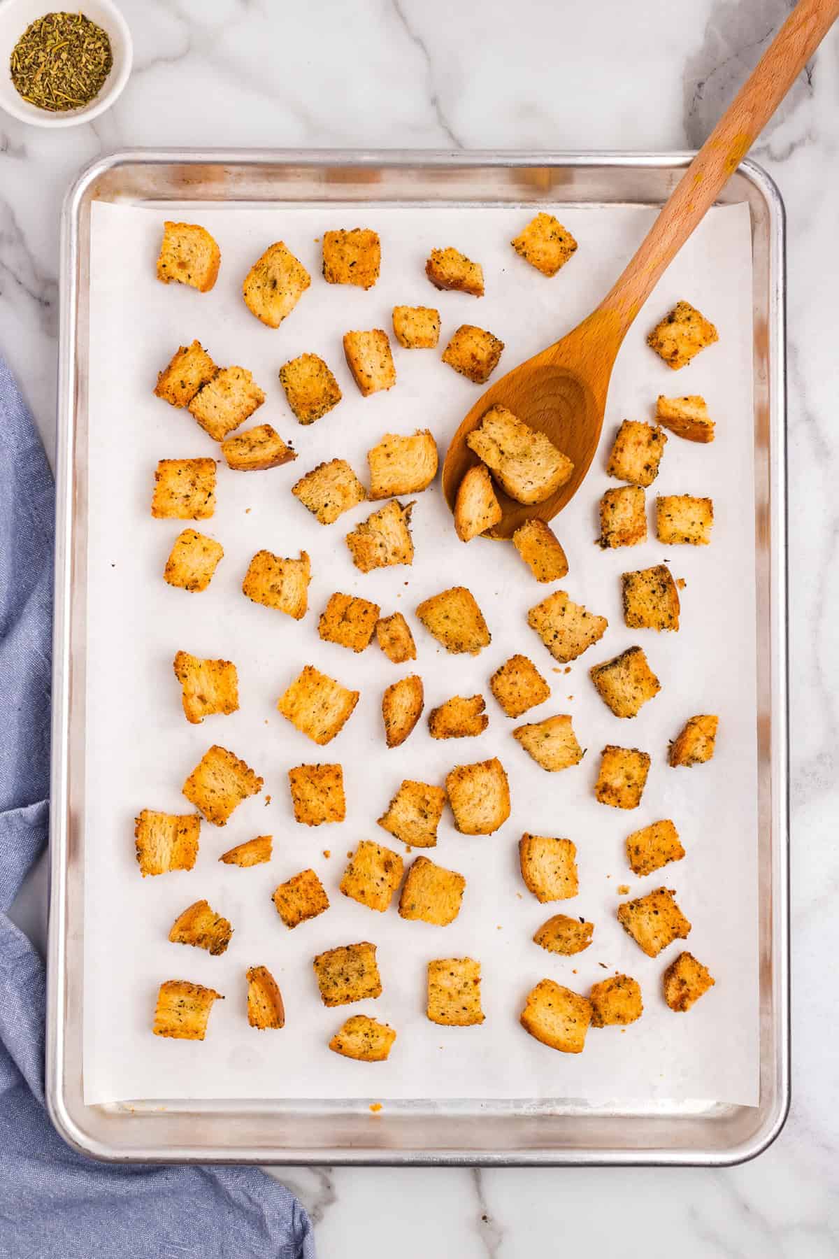 Tossing baked Homemade Croutons on baking sheet