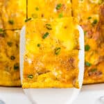 Using a spatula to lift one piece of Mashed Potato Egg Back from baking dish