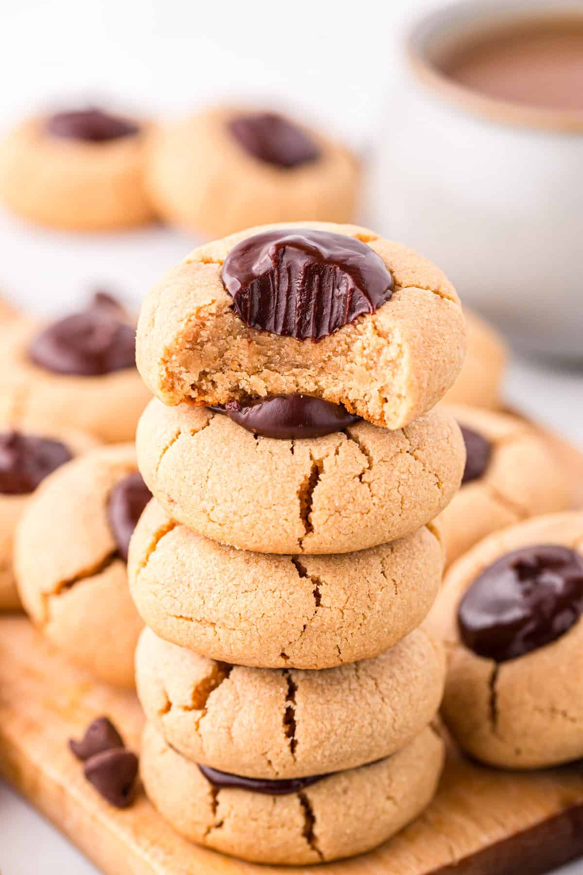 Peanut Butter Thumbprint Cookies stacked on wood cutting board with one bite taken