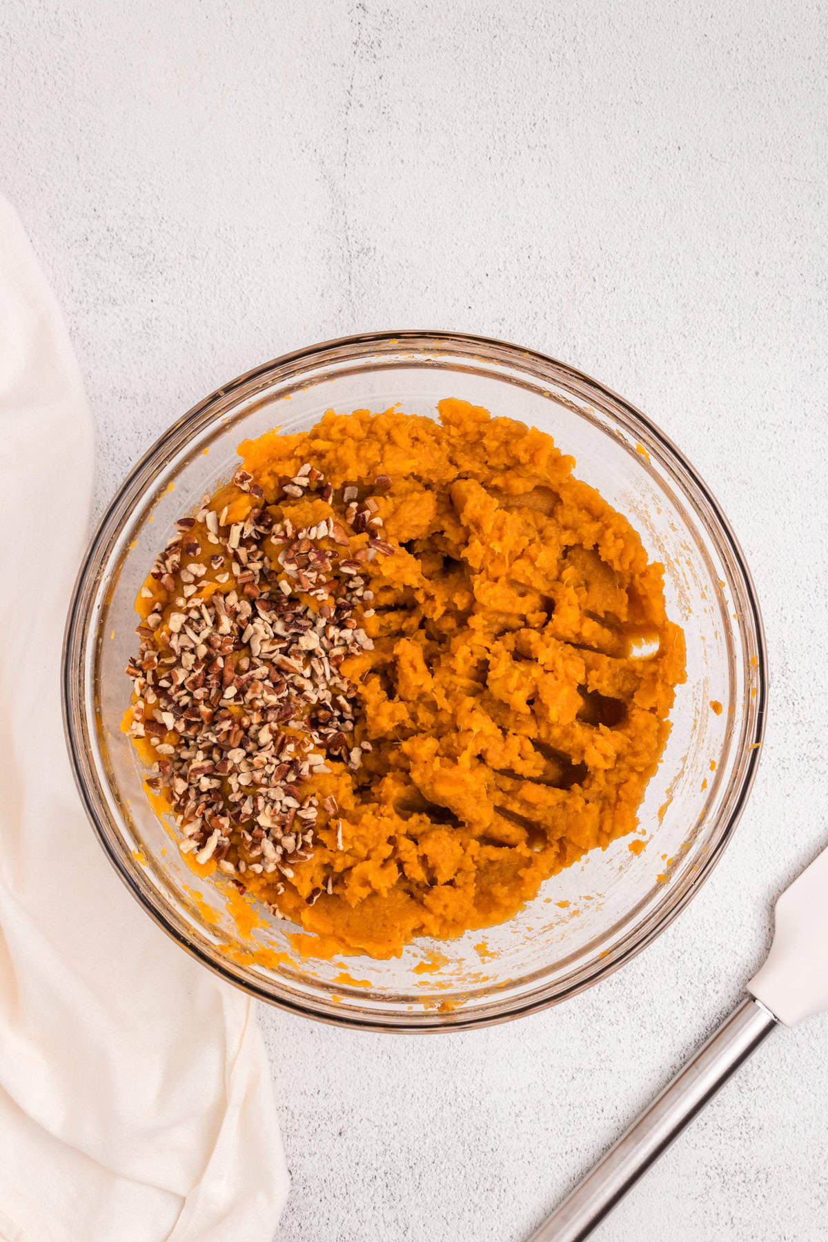 Overhead picture of glass bowl with mashed sweet potatos and pecans in it.