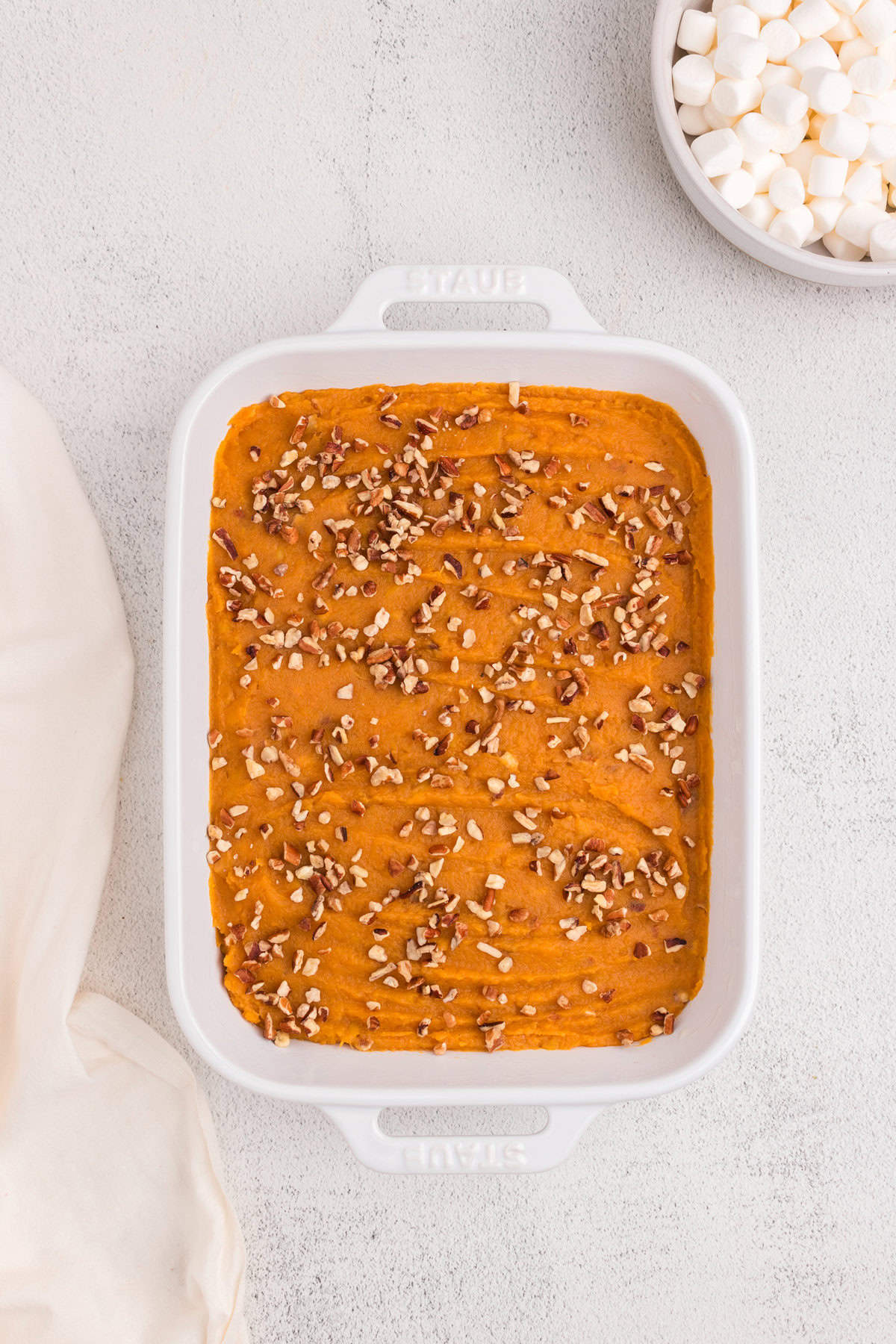 Overhead picture of white pan with mashed sweet potatos and pecans in it.