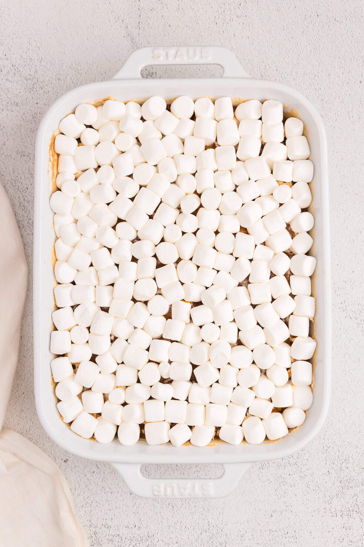 Overhead picture of white pan with marshmallows layered over the casserole unbaked.