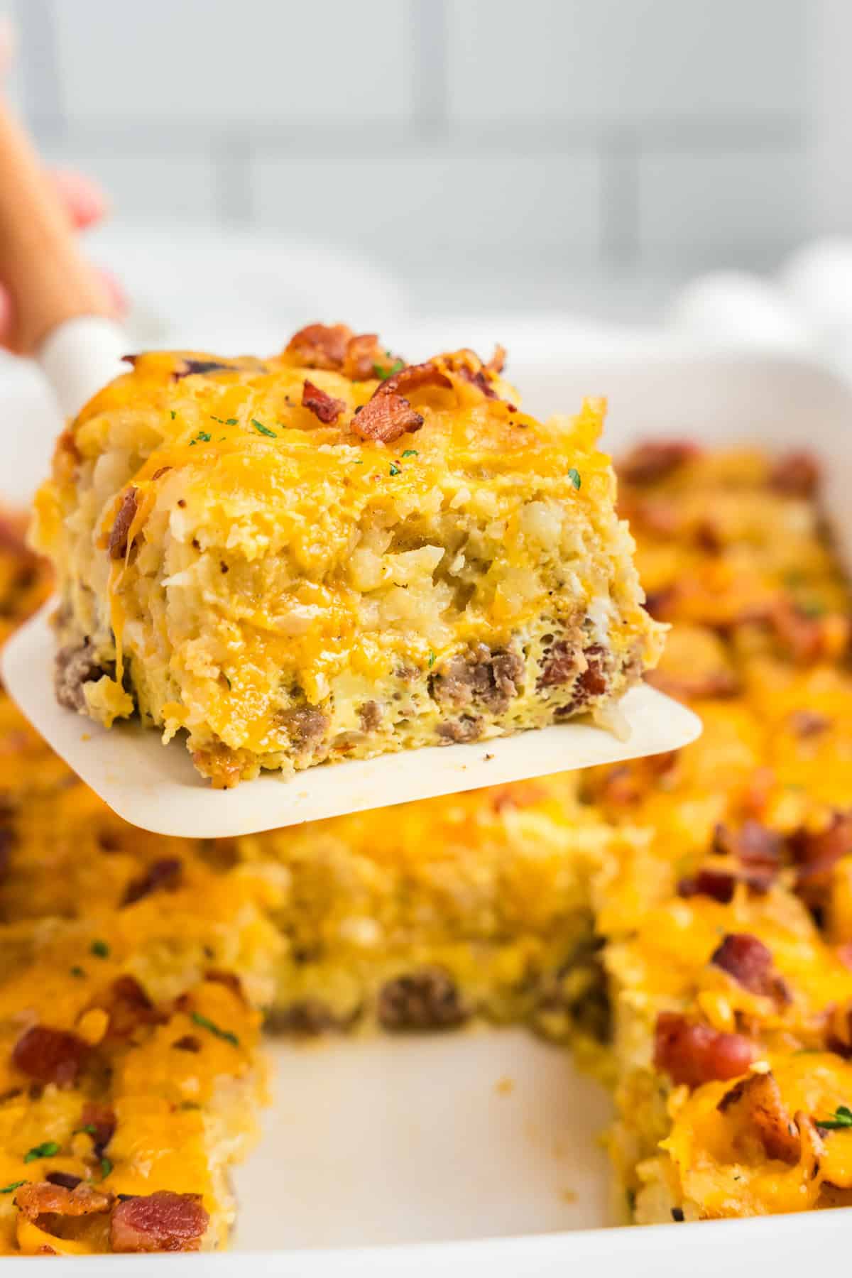 Spatula with a piece of breakfast casserole on it with casserole in the background