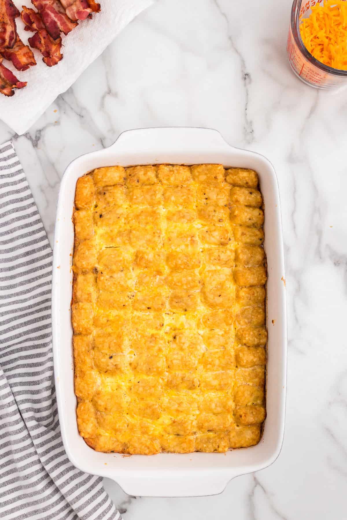 Overhead picture of tater tots layered ontop of eggs in white pan